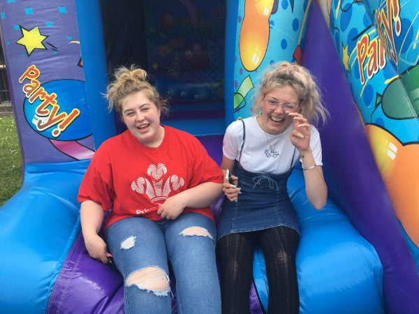 two young women laughing and smiling on a bouncy castle