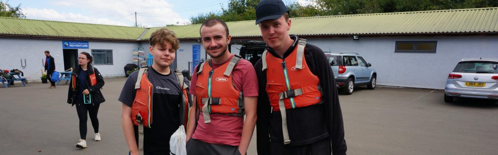 three young men in life jackets smiling