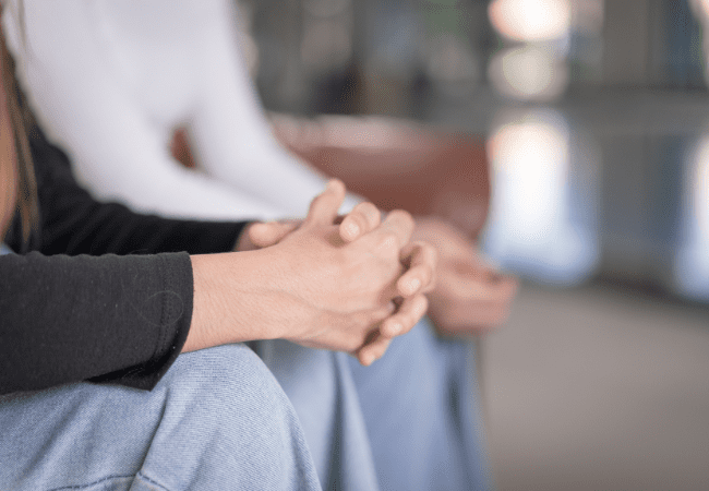 women's hands clasped together in her lap