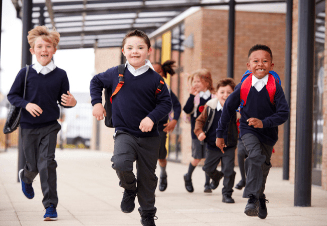 primary school age children in uniform running in playground