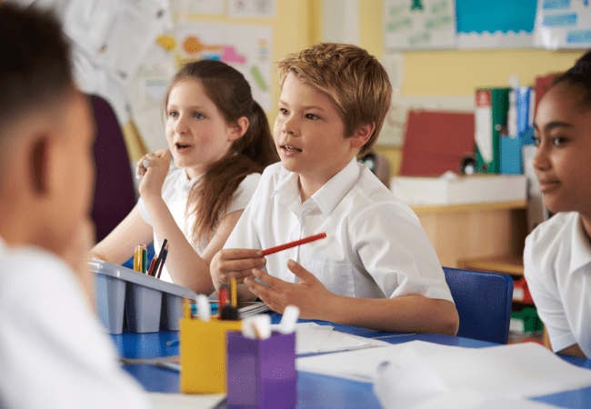 primary age children in uniform at desks in classroom